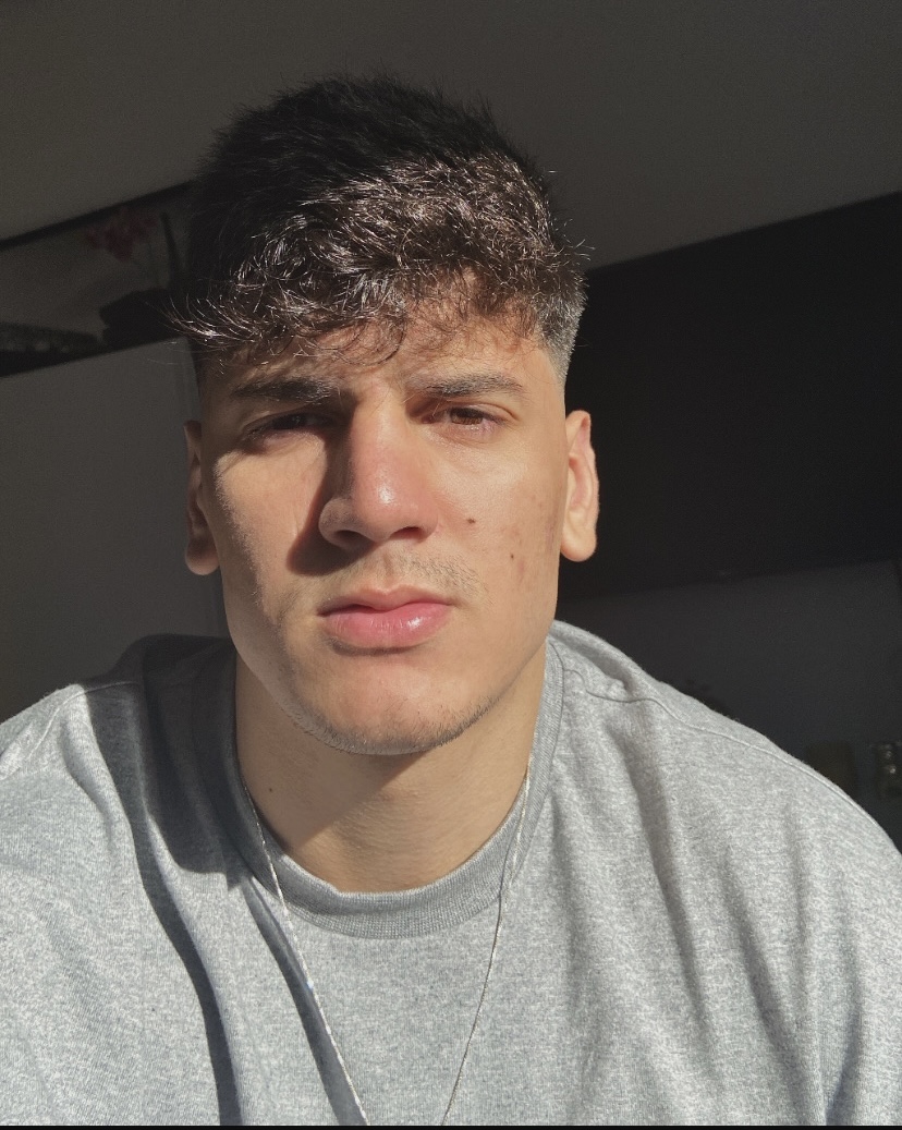 Gabriel Tavares usando uma camiseta cinza, iluminado pelo sol